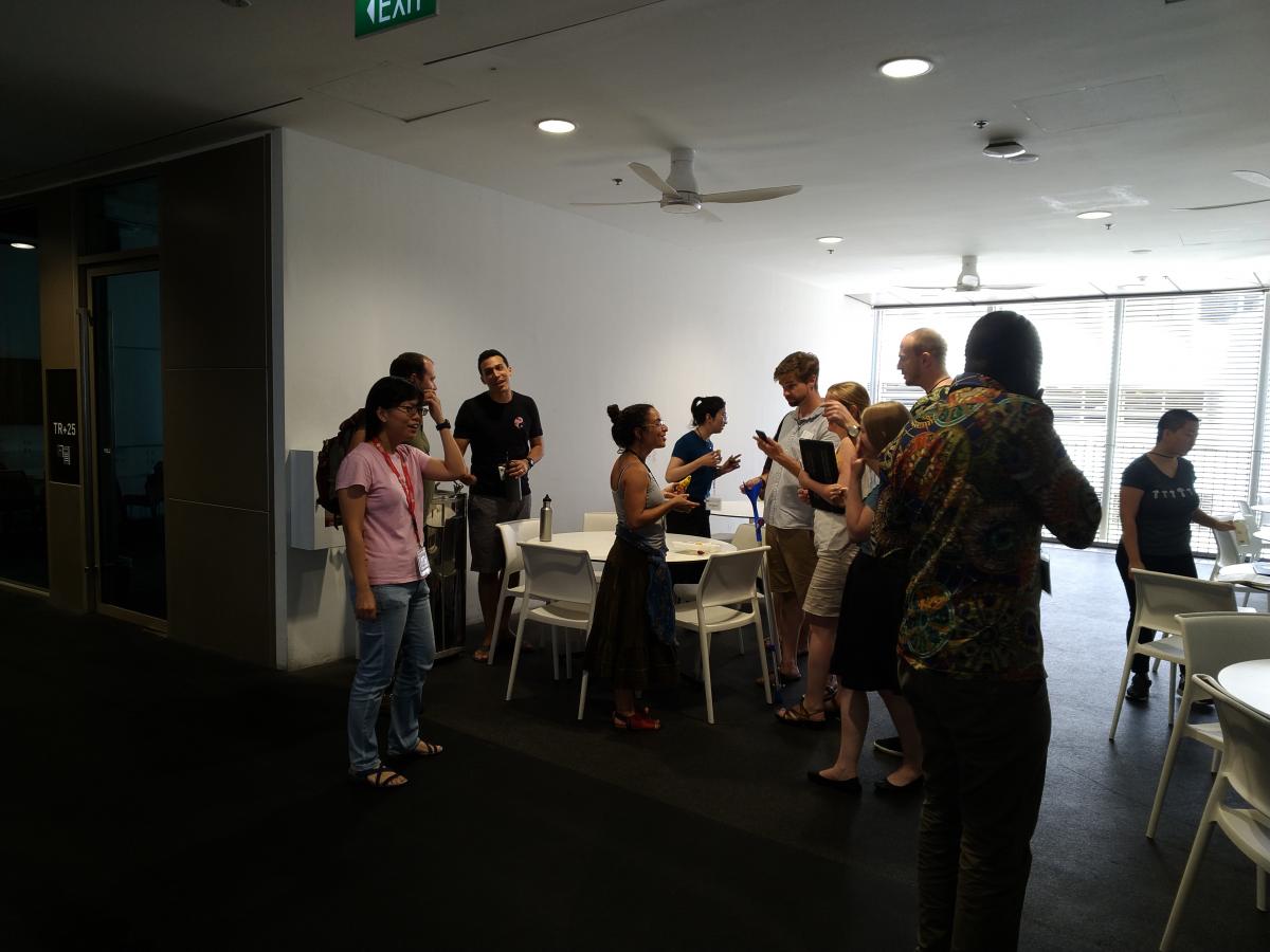Workshop participants stand in a common area, talking to each other.